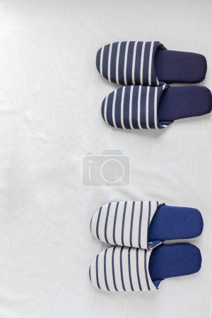 Photo for Two pairs of slippers on a white cloth background. Daily routine after marriage concept. - Royalty Free Image