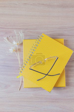Téléchargez les photos : Planificateurs jaunes avec des verres sur le dessus et des fleurs sauvages de côté sur la table en bois. bureau à domicile espace de travail - en image libre de droit