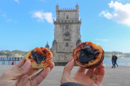 Téléchargez les photos : Couple mangeant des tartes à la crème anglaise devant la tour Belem lors de leur lune de miel - en image libre de droit