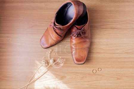 Photo for Men's leather shoes with wedding rings on a wooden background. - Royalty Free Image