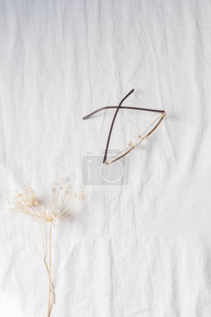 Téléchargez les photos : Vue du dessus des verres avec fleur séchée sur tissu de coton blanc. - en image libre de droit