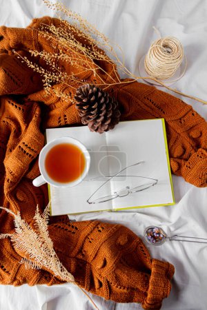 Foto de Composición de moda femenina. Jersey de punto de lana hembra caliente, té sobre fondo de sábana blanca. Composición otoñal. - Imagen libre de derechos