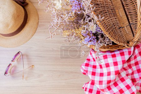 Foto de Vista superior de la cesta de picnic con un ramo de flores secas en el interior, gafas de sol y sombrero de paja - Imagen libre de derechos