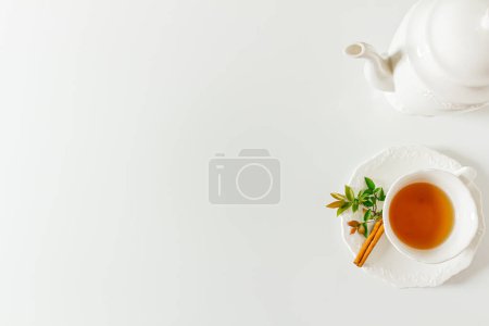 Foto de Taza de té con tetera, bolsa de té y hojas verdes sobre fondo blanco. Piso tendido, vista superior. - Imagen libre de derechos