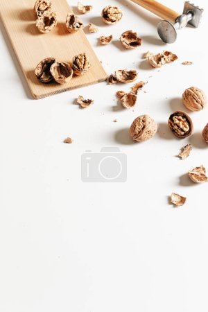 Foto de Composición otoñal con nueces y conchas vacías sobre tabla de madera sobre fondo blanco. - Imagen libre de derechos