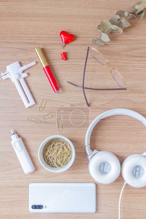 Photo for Workspace with headphone, paper cutter, electric eraser, paper clips and smartphone on wooden background. - Royalty Free Image