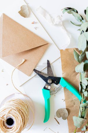Photo for Creative retro style composition of craft envelopes, blank paper sheet and eucalyptus branches on white background. Florist, flower shop, gift concept. - Royalty Free Image