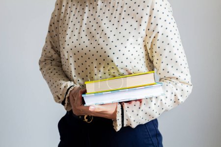 Foto de Mujer joven con una blusa de lunares sosteniendo libros - Imagen libre de derechos