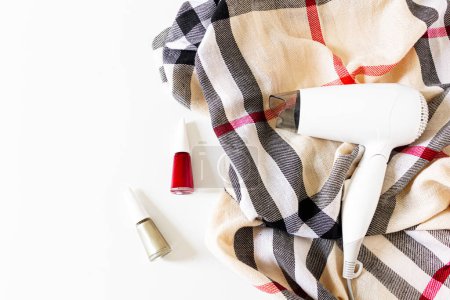 Foto de Collage de belleza con esmalte de uñas, bufanda y secador de pelo sobre fondo blanco. Piso tendido, vista superior. - Imagen libre de derechos