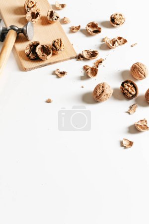 Foto de Composición otoñal con nueces y conchas vacías sobre tabla de madera sobre fondo blanco. - Imagen libre de derechos