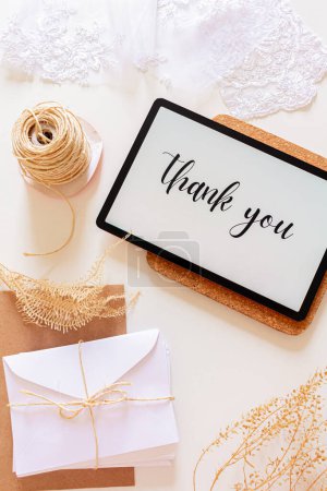 Foto de Vista superior de la tableta digital con frase Gracias en la pantalla con sobres y flores secas - Imagen libre de derechos