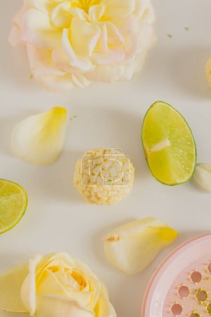 Téléchargez les photos : Bonbons au chocolat blanc avec tranches de citron et fleurs roses sur fond blanc. Style alimentaire. Réconfort du printemps et de l'été. - en image libre de droit