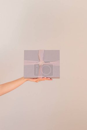 Photo for Female hand holding a linen fabric gift box. - Royalty Free Image