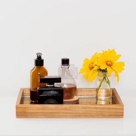 Téléchargez les photos : Vue rapprochée des flacons de parfum avec bouquet de fleurs jaunes sur plateau miroir. Composition esthétique minimaliste beauté. - en image libre de droit