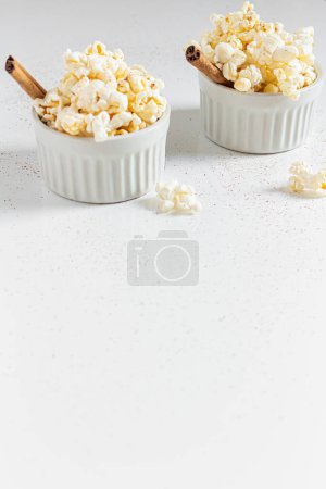 Photo for Cozy still life with popcorn in porcelain bowls decorated with cinnamon sticks. Autumn, winter food concept. - Royalty Free Image