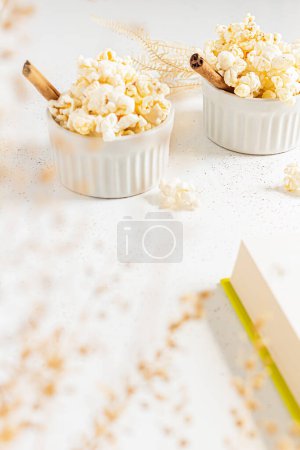 Photo for Cozy still life with popcorn in porcelain bowls decorated with cinnamon sticks. Autumn, winter food concept. - Royalty Free Image