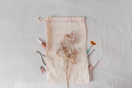 Foto de Blog de belleza, concepto de manicura con esmalte de uñas, bolsa de algodón y herramientas de manicura decoradas con flores lila - Imagen libre de derechos