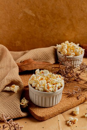 Photo for Cozy and aesthetic beige composition with popcorn in bowls and dried leaves around. Autumn, winter food concept. - Royalty Free Image