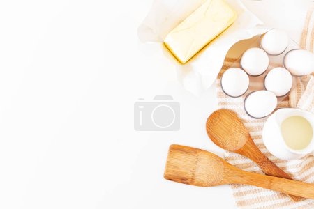 Foto de Menaje de cocina, concepto de preparación de pasteles sobre fondo blanco. vista superior de utensilios de madera, mantequilla, huevos y paño de cocina. - Imagen libre de derechos