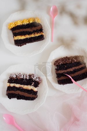 Photo for Top view of delicious chocolate cake slices in white plates. Party comfort food concept. - Royalty Free Image