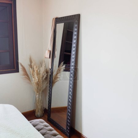 Foto de Elegante dormitorio con espejo y ramo de flores secas. Diseño clásico moderno. - Imagen libre de derechos