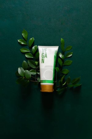 Foto de Crema cosmética vegana con hojas verdes aisladas sobre fondo verde profundo. Concepto de cuidado de la piel. - Imagen libre de derechos