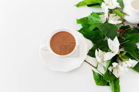 Foto de Vista superior de la taza de café con flores blancas y hojas verdes sobre blanco - Imagen libre de derechos