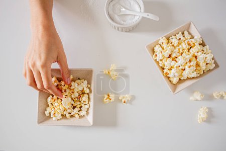 Photo for Female hand taking popcorn from white bowl. - Royalty Free Image