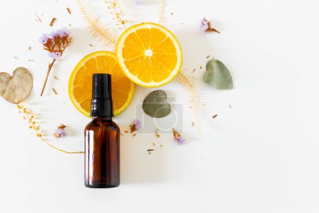 Photo for Beauty spa beige composition with amber bottle, orange slices and eucalyptus and flowers dried leaves on white background. Flat lay, top view. Female beauty treatment routine concept. - Royalty Free Image