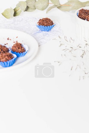 Photo for Homemade brigadeiro on blue paper baking cases on white background. Brazilian traditional recipe. Party snacks composition. - Royalty Free Image