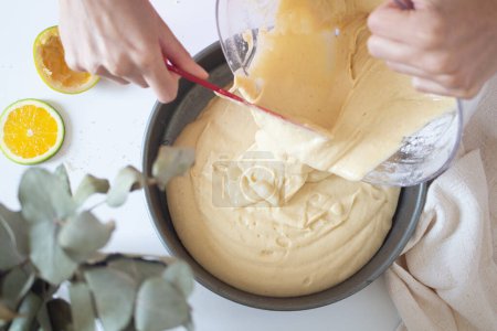 Téléchargez les photos : Vue de dessus des mains féminines versant de la pâte dans le moule de cuisson dans la cuisine - en image libre de droit