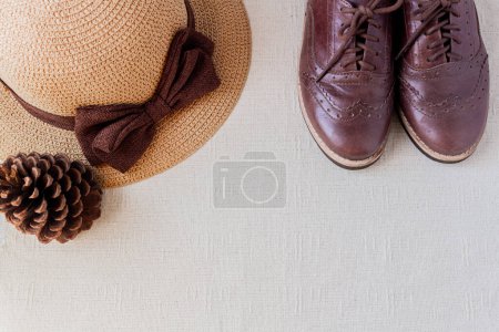 Téléchargez les photos : Chaussures oxford Vintage femme brun foncé, chapeau de paille et pin sur fond blanc. Concept de mode. Blog, blogueur, médias sociaux. - en image libre de droit
