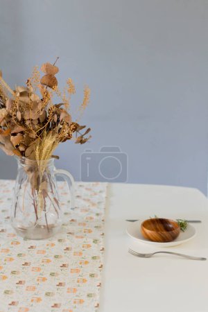 Foto de Vajilla sobre tela de lino con ramo de flores secas en jarrón - Imagen libre de derechos