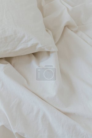 Foto de Sábana de algodón beige y almohada. Concepto de cama mínima. - Imagen libre de derechos