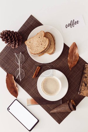 Téléchargez les photos : Concept de pause café confortable. Composition du petit déjeuner avec tasse de café, pain tranché, feuilles séchées et une carte avec le message : "café". - en image libre de droit