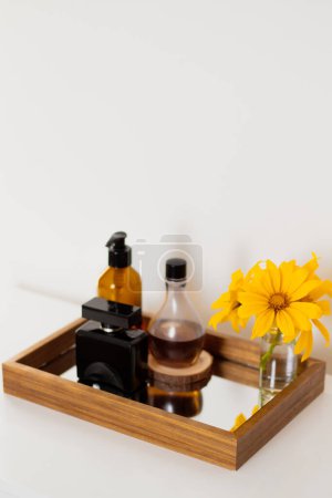 Foto de Vista de cerca de botellas de perfume con ramo de flores amarillas en bandeja de espejo. Composición estética minimalista de belleza. - Imagen libre de derechos
