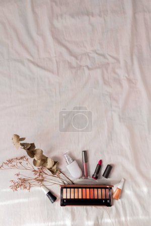 Foto de Accesorios de estilo femenino: flores secas y cosméticos sobre fondo textil blanco. - Imagen libre de derechos