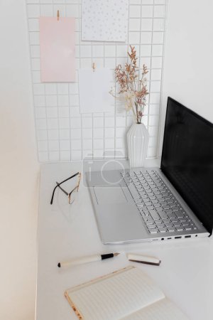 Téléchargez les photos : Bureau à domicile espace de travail sur bureau blanc avec ordinateur portable, ordinateur portable et lunettes - en image libre de droit