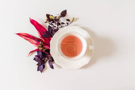 Téléchargez les photos : Vue du dessus de la tasse de composition du thé au gingembre avec des feuilles violettes et roses sur fond blanc. - en image libre de droit