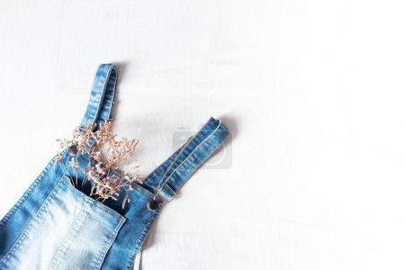 Photo for Feminine spring and summer fashion composition with denim overralls on white bed sheet background. Flat lay, top view. Vintage clothes collage. Female fashion blog and social media concept. - Royalty Free Image