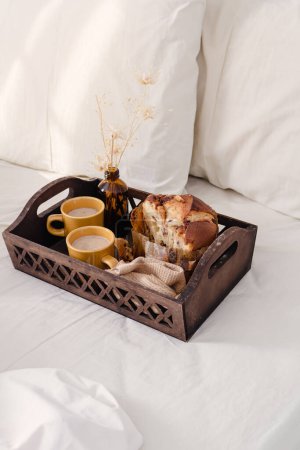 Foto de Desayuno en bandeja vintage de madera oscura en la cama con sábana beige claro y almohadas. concepto romántico de mañana. - Imagen libre de derechos