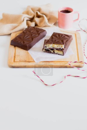 Foto de Composición con barras de chocolate sobre tabla de madera y taza de café sobre fondo - Imagen libre de derechos