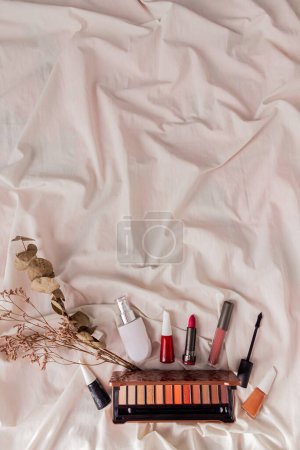 Téléchargez les photos : Accessoires de style féminin : fleurs séchées et cosmétiques sur fond textile blanc. - en image libre de droit