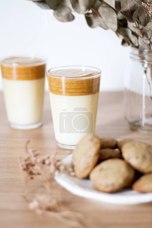 Téléchargez les photos : Café Dalgona au lait, vase d'eucalyptus séché et biscuits sur table en bois. - en image libre de droit
