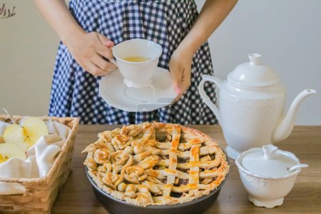 Téléchargez les photos : Plan recadré de femme en robe à carreaux buvant du thé avec tarte aux pommes. - en image libre de droit