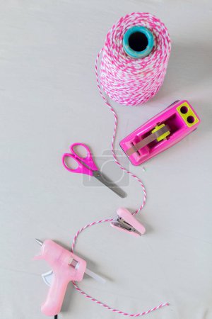 Photo for Craft essentials. Pink string, scissors, stapler, duct tape holder and hot glue gun on a white background. Do it yourself concept. - Royalty Free Image