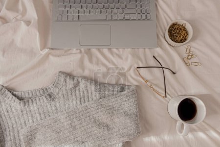 Foto de Portátil, taza de té, suéter de punto y bufanda sobre fondo blanco - Imagen libre de derechos