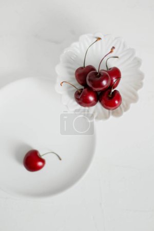 Foto de Cerezas en un tazón, sobre fondo blanco. Composición minimalista. - Imagen libre de derechos