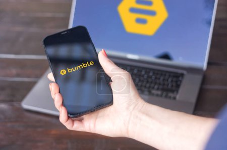 Photo for WROCLAW, POLAND - SEPTEMBER 14, 2023:Bumble logo, online dating and networking application, displayed on the iPhone screen held in hand with MacBook Pro in the background - Royalty Free Image