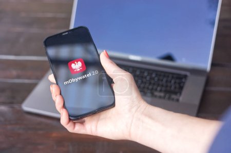Photo for WROCLAW, POLAND - SEPTEMBER 14, 2023:mObywatel logo (Polish application offering mobile versions of documents as digital services), displayed on an iPhone screen with MacBook Pro in the background. - Royalty Free Image